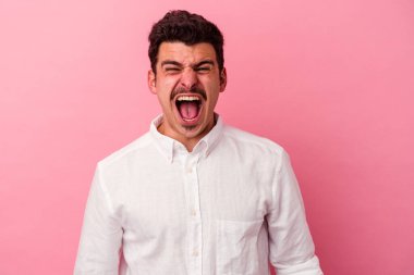 Pembe arka planda izole edilmiş genç beyaz adam çok sinirli ve agresif çığlıklar atıyor..