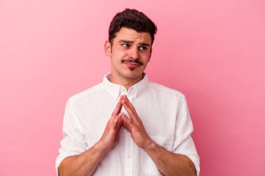 Kafkasyalı genç bir adam pembe arka planda izole edilmiş bir plan yapıyor, bir fikir kuruyor..