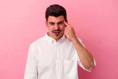 Pembe arka planda izole edilmiş genç beyaz adam işaret parmağıyla hayal kırıklığı jesti gösteriyor..