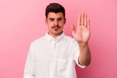Pembe arka planda izole edilmiş genç beyaz adam elini uzatmış, dur işareti göstererek seni engelliyor..