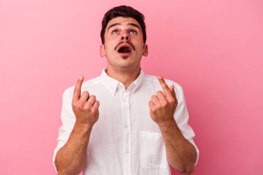 Pembe arka planda izole edilmiş beyaz bir adam ağzı açık bir şekilde üst tarafı işaret ediyor..