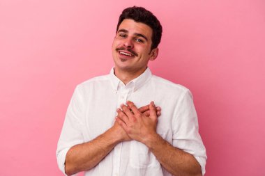 Pembe arka planda izole edilmiş genç beyaz bir adam, dostane bir ifadeye sahip, avuçlarını göğsüne bastırıyor. Aşk konsepti.