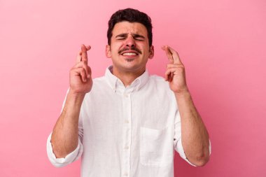 Pembe arka planda izole edilmiş beyaz bir adam şans getirsin diye dua ediyor.