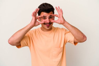 Beyaz arka planda izole edilmiş genç beyaz bir adam gözlerinde sorun olmadığını gösteriyor.