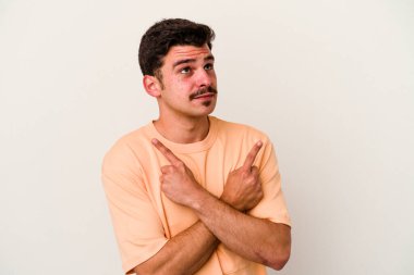 Beyaz arka plan noktalarında izole genç beyaz adam, iki seçenek arasında seçim yapmaya çalışıyor.