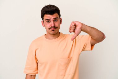 Beyaz arka planda izole edilmiş genç beyaz adam baş parmağını aşağı gösteriyor, hayal kırıklığı konsepti..