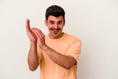 Beyaz arka planda izole olmuş genç beyaz bir adam enerjik ve rahat hissediyor, ellerini ovuşturuyor..