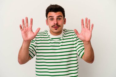 Beyaz arka planda izole edilmiş genç beyaz adam gökyüzüne haykırıyor, yukarı bakıyor, hayal kırıklığına uğramış..