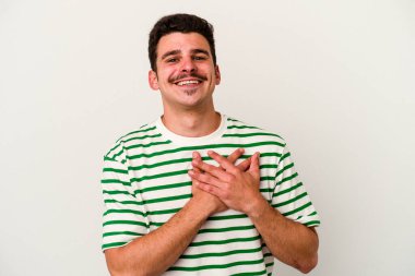 Beyaz arka planda izole edilmiş beyaz tenli genç bir adam, dostane bir ifadeye sahip, avuçlarını göğsüne bastırıyor. Aşk konsepti.