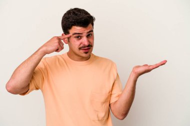 Beyaz arka planda izole edilmiş genç beyaz bir adam elinde bir ürün tutuyor ve.