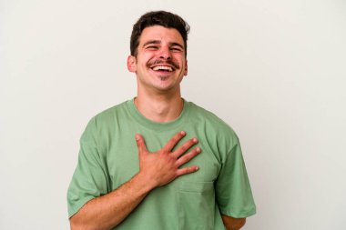 Beyaz arka planda izole genç beyaz adam yüksek sesle gülüyor elini göğsüne koyuyor..