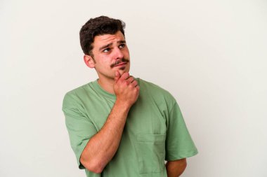 Beyaz arka planda soyutlanmış genç beyaz bir adam düşünüyor ve yukarı bakıyor, yansıtıyor, düşünüyor, hayal kuruyor..