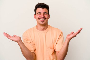 Beyaz arka planda izole genç beyaz adam kollarıyla ölçek yapar, mutlu ve kendinden emin hisseder..