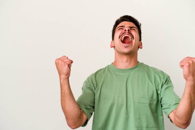 Beyaz arka planda izole edilmiş genç beyaz bir adam zaferden sonra yumruğunu kaldırıyor, kazanan konsept.