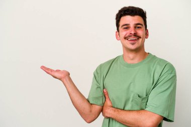 Beyaz arka planda izole edilmiş genç beyaz bir adam bir palmiye üzerinde fotokopi alanı gösteriyor ve belinde başka bir el tutuyor..