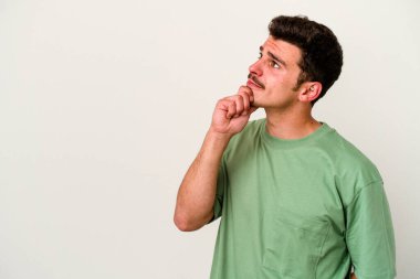 Beyaz arka planda izole edilmiş genç beyaz bir adam rahatlamış bir şeyin fotokopi odasına baktığını düşünüyor..