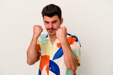 Beyaz arka planda izole edilmiş genç beyaz bir adam yumruğunu kameraya gösteriyor, agresif bir yüz ifadesi..