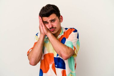 Beyaz arka planda izole edilmiş genç beyaz adam esniyor. Ağzı eliyle kapatan yorgun bir hareket sergiliyor..