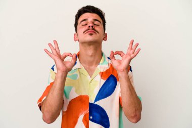 Beyaz arka planda izole edilmiş genç beyaz adam yoğun bir günün ardından rahatlıyor. Yoga yapıyor..