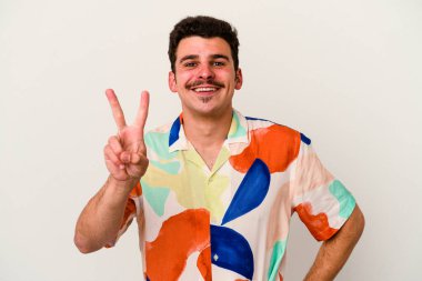 Beyaz arka planda izole edilmiş genç beyaz adam iki numarayı parmaklarıyla gösteriyor..