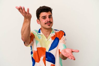 Beyaz arka planda izole genç beyaz adam kollarıyla ölçek yapar, mutlu ve kendinden emin hisseder..