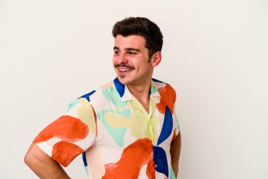 Beyaz arka planda izole genç beyaz adam mutlu bir şekilde gülüyor ve ellerini karnının üstünde tutarak eğleniyor..