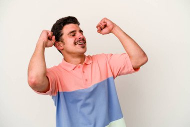 Beyaz arka planda izole genç beyaz adam özel bir günü kutluyor, atlıyor ve enerjiyle kollarını kaldırıyor..