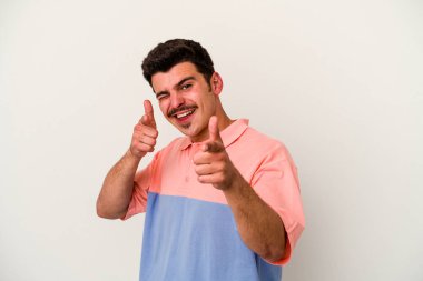 Beyaz arka planda izole edilmiş genç beyaz adam parmaklarıyla ön tarafı işaret ediyor..