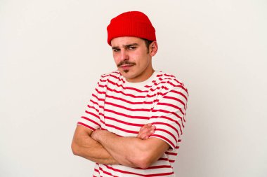 Beyaz arka planda izole edilmiş, hoşnutsuzca kaşlarını çatmış, kollarını kavuşturmuş genç beyaz bir adam..
