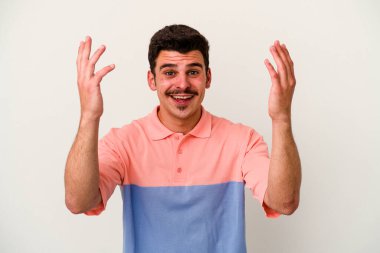 Beyaz arka planda izole genç beyaz adam hoş bir sürpriz alıyor, heyecanlı ve el kaldırıyor..