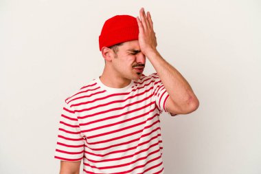 Beyaz arka planda izole edilmiş genç beyaz bir adam bir şeyi unutuyor. Alnına avuç içi ve gözlerini kapayarak vuruyor..