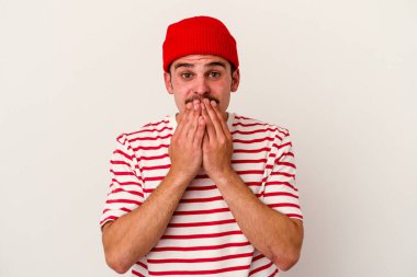 Beyaz arka planda izole edilmiş genç beyaz adam elleriyle ağzını kapatırken şok oldu..