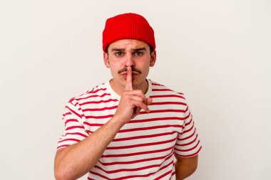 Beyaz arka planda izole edilmiş genç beyaz bir adam ya sır saklıyor ya da sessizlik istiyor..