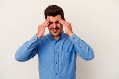 Beyaz arka planda izole olmuş genç beyaz bir adam başı ağrıyor, yüzüne dokunuyor..