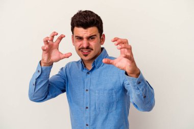 Beyaz arka planda izole edilmiş genç beyaz bir adam pençelerini kedi taklidi yaparken gösteriyor, agresif bir hareket..