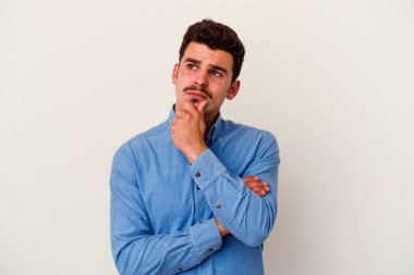 Beyaz arka planda soyutlanmış genç beyaz bir adam düşünüyor ve yukarı bakıyor, yansıtıyor, düşünüyor, hayal kuruyor..