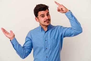 Beyaz arka planda izole edilmiş genç beyaz bir adam elinde bir ürün tutuyor ve.