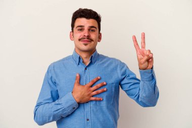 Beyaz arka planda izole edilmiş genç beyaz adam yemin ediyor, elini göğsüne koyuyor..