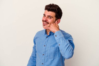 Beyaz arka planda izole edilmiş genç beyaz bir adam parmakları olan bir cep telefonu hareketi gösteriyor..