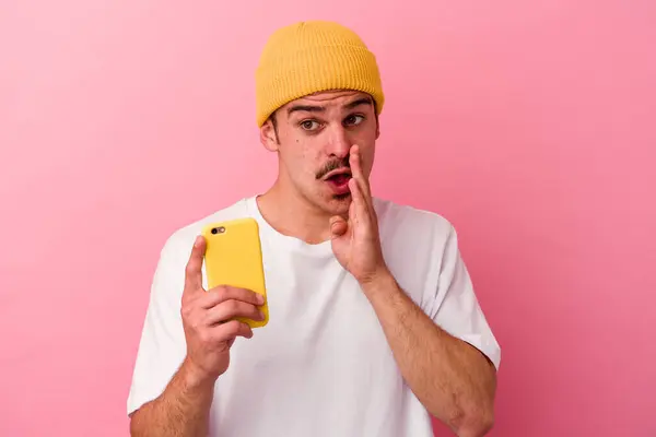 Młody Biały Mężczyzna Trzymając Telefon Komórkowy Odizolowany Różowym Tle Mówi — Zdjęcie stockowe