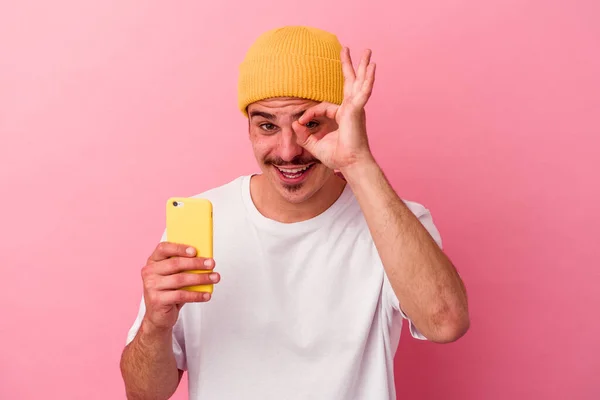 Młody Biały Mężczyzna Trzymając Telefon Komórkowy Odizolowany Różowy Tło Podekscytowany — Zdjęcie stockowe