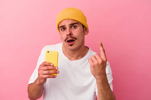 Młody Biały Mężczyzna Trzymając Telefon Komórkowy Odizolowany Różowym Tle Mając — Zdjęcie stockowe