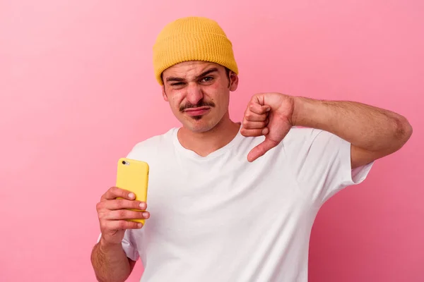 Młody Biały Mężczyzna Trzymający Telefon Komórkowy Różowym Tle Wykazujący Niechęć — Zdjęcie stockowe