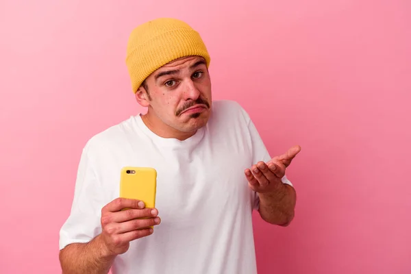 Joven Hombre Caucásico Sosteniendo Teléfono Móvil Aislado Sobre Fondo Rosa —  Fotos de Stock