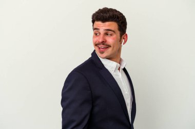 Beyaz arka planda izole edilmiş kablosuz kulaklık takan beyaz iş adamı gülümsüyor, neşeli ve keyifli görünüyor..