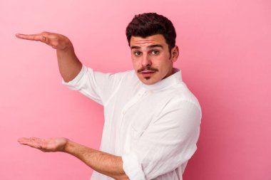 Pembe arka planda izole edilmiş genç beyaz adam elleri arasında bir fotokopi alanı tutuyor..