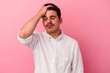 Pembe arka planda izole edilmiş genç beyaz adam yorgun ve uykulu..