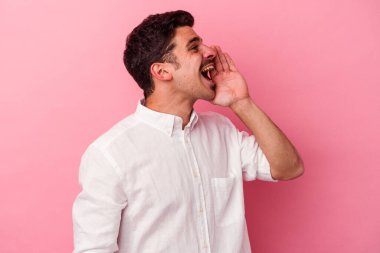 Pembe arka planda izole edilmiş genç beyaz adam bağırıyor ve avuç içini açık tutuyor..