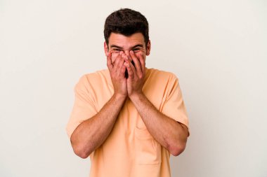 Beyaz arka planda izole olmuş genç beyaz bir adam bir şeye gülüyor, ağızlarını ellerle kapatıyor..