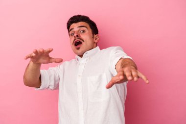 Pembe arka planda izole genç beyaz adam yakın bir tehlike nedeniyle şoka uğruyor.